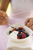Woman eating fresh berries with yoghurt