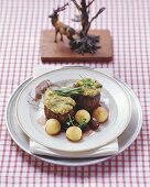 Venison medallions with herb and nut crust and grape sauce
