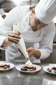 Chef piping cream onto berry desserts