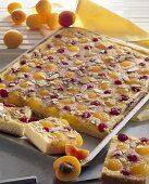 Apricot and cherry cake with flaked almonds on baking tray