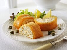 Filled salmon roulade with lemon wedges and capers