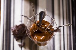 Schokoladenmousse im Glas mit mehreren Löffeln (Draufsicht)
