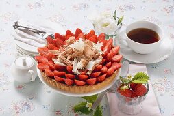 Strawberry tart with chocolate shavings, cup of coffee