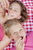 Two girls with cherries on a picnic cloth