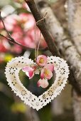 A metal heart and japonica hanging on a tree