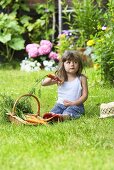 Kleines Mädchen mit Möhren auf Gartenwiese