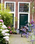 Fahrrad vor grün lackierten Eingangstüren im englischen Stil in begrüntem Innenhof