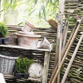 Garden tools and flowerpots by willow hurdle