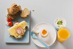 Frühstücksei und Vollkornbrot mit Magerquark, Käse und Radieschen