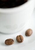 Drei Kaffeebohnen mit einer Tasse Kaffee