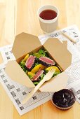 Rocket salad with fried tuna and orange segments in a take-away box