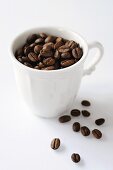 Coffee beans in and beside cup