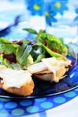 Baguette slices with toasted Camembert and salad