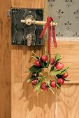 Wreath of holly leaves & ornamental apples on door handle