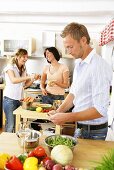 Three young people preparing vegetables in kitchen