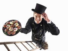 Chimney sweep on ladder holding plate of muffins