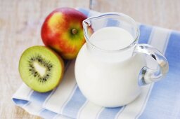 Milch im Glaskrug, Apfel und Kiwi