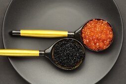Salmon caviar & sturgeon caviar in two wooden spoons (overhead view)