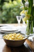 Ribbon pasta with butter on wooden table with spring flowers