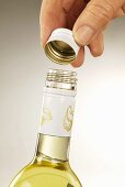 Opening bottle of white wine with metal screw-top cap