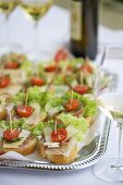 Canapes with ham, cheese and tomato on silver platter