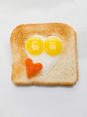 Fried eggs in heart-shaped hole in slice of toast
