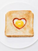 Heart-shaped fried egg with ketchup in slice of toast
