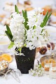 Vase of hyacinths and pear blossom on laid table