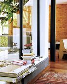 Stack of books on windowsill with brick wall in background