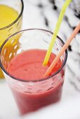 A glass of strawberry smoothie with straws