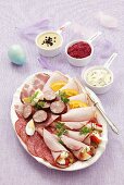 Kalte Platte mit Salami, Schinkenröllchen, Wurst und verschiedenen Saucen