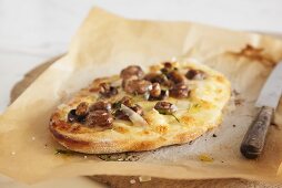 Small mushroom and Pecorino pizza on baking parchment