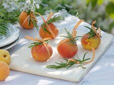 Rosemary sprigs tied to apricots with ribbon