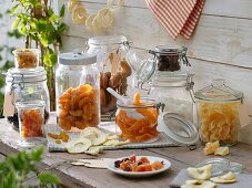 Assorted dried fruit in storage jars on wooden table