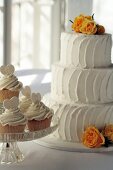 Three-tiered white wedding cake and lemon cupcakes
