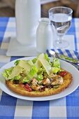 Pizza topped with chicken, romaine lettuce and cheese