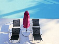 Loungers and sunshade by swimming pool