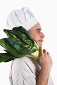 Chef with knife in his mouth and chard on his shoulder