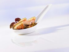 Quail appetiser with lentils and fig on a porcelain spoon