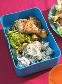 Grilled chicken leg with potato salad in picnic box