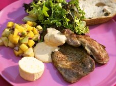 Plate of grilled meat, sambal sauce and avocado & mango salad