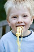 Small boy eating ribbon pasta