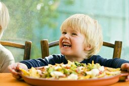 Laughing boy, nachos with tomato salsa and guacamole