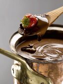 Strawberry in melted chocolate on a wooden spoon