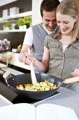 Man and woman stirring vegetables in wok