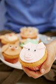 Hand holding muffin with pig's face