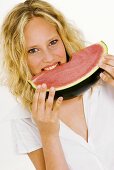 Blonde Frau beisst in eine Melonenspalte