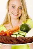 Young girl looking at plate of vegetables