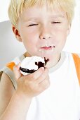Blond boy enjoying a chocolate-covered marshmallow wafer