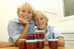 Two blond boys with jars of strawberry jam